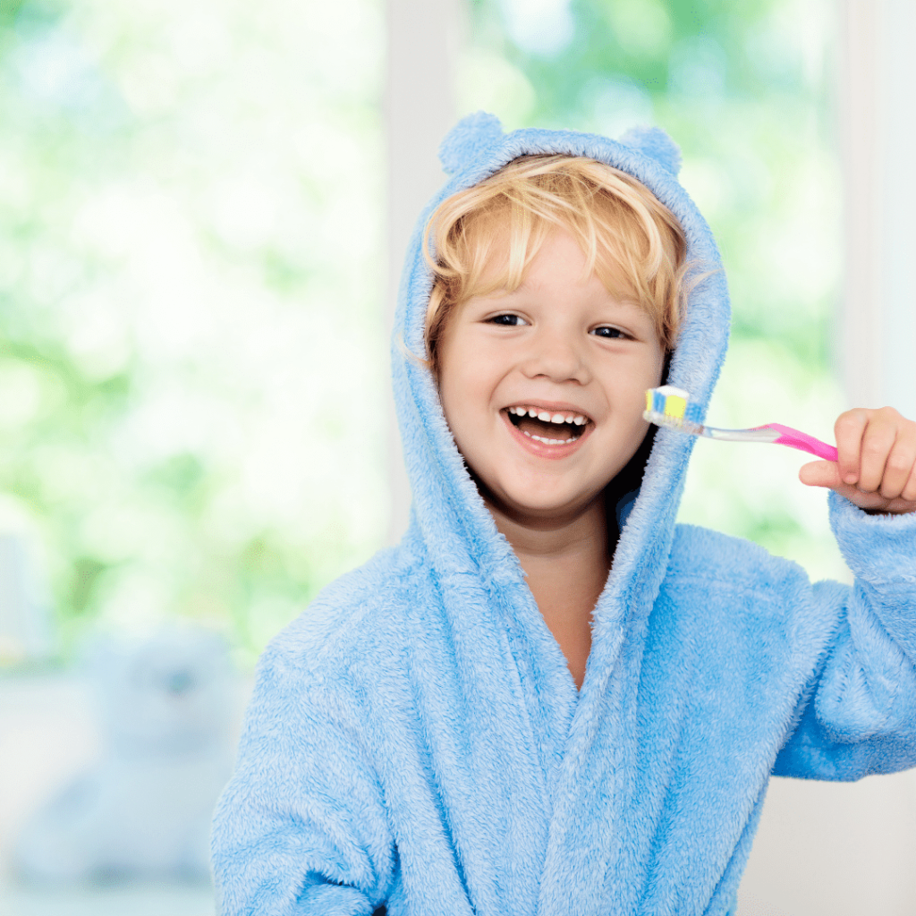 child laughing smiling with blue robe and toothbrush in his hand