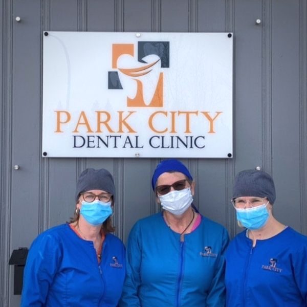 three dental assistant women standing in front of park city dental sign outside